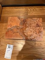 Two angles of one wooden terrain sculpture showing carved details and wood grain
