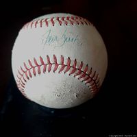 Vintage white baseball with red stitching, showing wear and dirt marks. Clear blue ink signature by David Justice visible on the ball.