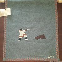 Full view of gray wool felt panel with embroidered hunter and seal, multicolor blanket-stitched border and signature visible