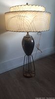 Full view of the lamp showing the metal base, body, and wire frame stand with attached lampshade.