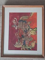 Full view of the vintage watercolor painting in a wooden frame with white matting, showing colorful abstract representation of a Mayan or Aztec god.