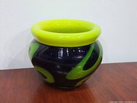 Front and side views of the small, thick glass Bohemia vase with swirling yellow design on black base.