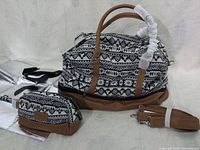 Front and side view of matching travelling bag, cosmetic bag and shoulder strap showing black and white pattern with brown accent base.