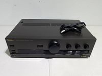 Front view of black Technics SU-G50 stereo integrated amplifier with power cord on top.