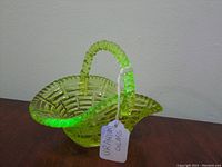 Uranium glass basket glowing under black light, showing vibrant green glow and textured handle.