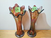 Front view of two amethyst carnival glass vases with swung rims and ribbed texture