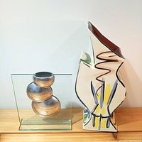 Modern ceramic vase with abstract painted design, paired with silver-toned sculptural piece in glass base