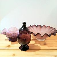 Front angle showing all three amethyst glass pieces: apothecary jar with lid, smaller edge bowl, larger scalloped edge bowl