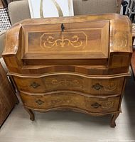 Full front view of desk showing drop-front panel, serpentine drawer fronts and cabriole legs
