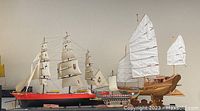 Photo showing three model ships side by side on a shelf: Japanese Junk, Roman Warship, and Cutty Sark style ship.