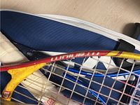 Close-up of yellow Platinum tennis racket with visible string and part of blue bag