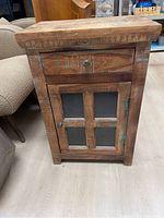 Front view of reclaimed wood side cabinet showing drawer and cross-design glass panel door with metal knobs.