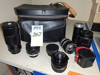 Overview of all lenses, teleconverters, and leather camera case displayed on table