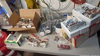 Overview on workbench: four boxes, styrofoam trays with two buildings, assorted packaged figurines and bagged trees