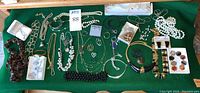 Overall lot layout showing assorted necklaces, bracelets, earrings, and a Timex watch on green cloth.