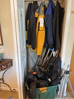 Multiple jackets hanging and bags plus tripod visible in storage bin