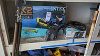 Box with Intex Explorer K2 2-person inflatable kayak image and electric pump in front with hoses and power cord coiled.