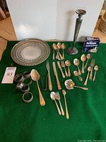 Full lot arranged on green cloth showing plate, candlestick, flatware, napkin rings and other pieces