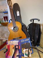 Full view showing guitar, gig bag, hard case, stand and books