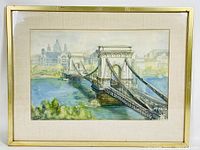 Framed and matted print showing a large suspension bridge over a river with city buildings in the background.