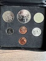 Close up of the 7 uncirculated Canadian coins set in black foam insert showing all coin denominations and faces including one dollar, 50 cent, 25 cent, dime, nickel, and two pennies.