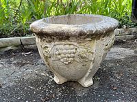Side view of concrete planter showing grapevine motif and weathered surface.