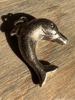 Front and side view of gold dolphin pendant showing overall shape and texture.