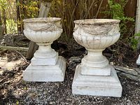 Two concrete urns side by side outdoors, front view