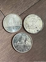 Three silver dollar coins showing reverses of 1939, 1949, and 1953 dates
