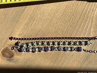 Photo of three silver bracelets laid out to show length and details in sunlight on wood surface.