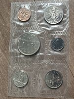 Clear view of six Canadian coins sealed in original clear plastic packaging with various coin sizes visible including penny and dollar coin.