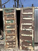Full front view of two tall Victorian pocket doors side by side showing extensive paint peeling and seven panel design.