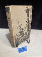 Front cover of the 1923 Tarzan and the Golden Lion book showing illustrated cloth binding featuring a man riding an elephant and jungle scene.