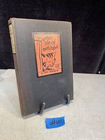 Front cover showing black hardcover with orange illustrated label featuring cat and title.