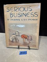 Front cover of Serious Business book showing title, authors, and illustration of two children playing or crouching, with visible age wear.