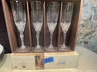 Four vintage Crystal d'Arques champagne flute glasses in original box labeled Constance with etched diamond pattern near the base of the bowl.