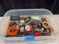 Plastic container filled with a large assortment of antique and vintage buttons in various shapes, sizes, and materials including Bakelite and mother of pearl, with visible wear consistent with age.
