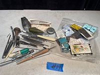 Overview of vintage sewing and craft tools with multiple small razor blade packs and pins