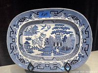 Photo of the front of the antique blue and white Asian platter showing detailed landscape and border patterns