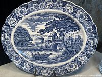 Set of three blue and white antique porcelain platters with scenic bridge and floral patterns.