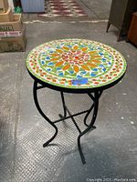 Full view of round iron side table with mosaic top.
