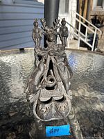 Full view of the cast iron match holder showing the overall design and shape on a glass table outside.