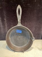 Front view of vintage cast iron frying pan showing decorative handle and pouring spout.