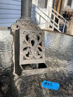Front view of the vintage cast iron match holder showing decorative scrollwork and heart-shaped cutout on front panel.