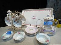 Full view of the vintage tea set including tray, cups, saucers, spoons, small dishes, glass teapot and warmer stand, and cup rack.