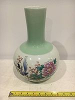 Full view of Chinese tall porcelain vase showing floral and bird painted design and ruler for scale.