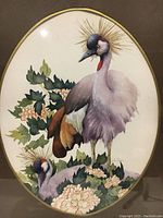 Close-up photo of the watercolor painting showing two birds and floral elements with gold dust accents around the larger bird's head.