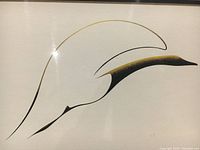 Close-up of stylized bird artwork in black and gold lines on white background under glass.