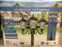 Front and side of unopened box showing LED outdoor post lantern with three lantern lights and product features
