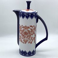 Front and side view of 12 inch tall Bombay porcelain coffee/tea pot showing cobalt blue handle, spout and lid with coral floral decorative motif on white background.
